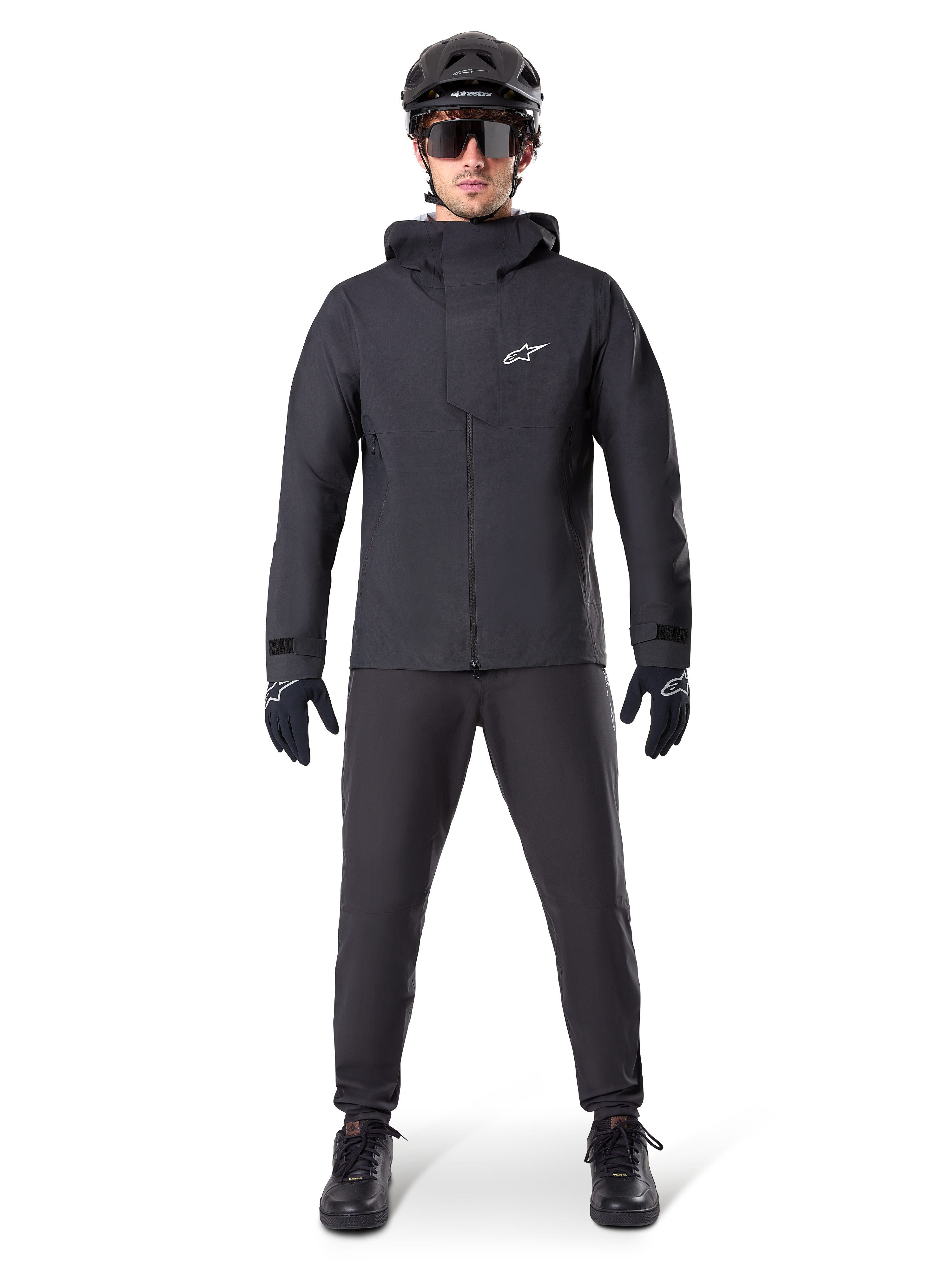 Alpinestars A-Dura Waterproof Pants, svarta MTB-byxor, bärs som en del av en komplett helsvart mountainbike-utrustning inklusive en teknisk vattentät jacka, svart hjälm, solglasögon och handskar, designade för terrängkörning i vått väder.