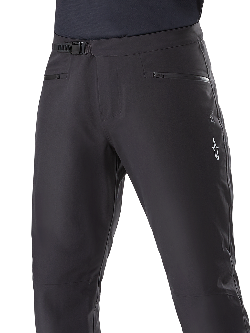 Alpinestars A-Dura Waterproof Pants, mountainbike-byxor, svarta, närbild av midjan som visar spärrspänne och fickor med dragkedja, vit Alpinestars-logotyp på låret, slitstarkt textilmaterial för terrängcykling i vått väder