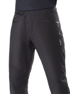 Alpinestars A-Dura Waterproof Pants, mountainbike-byxor, svarta, närbild av midjan som visar spärrspänne och fickor med dragkedja, vit Alpinestars-logotyp på låret, slitstarkt textilmaterial för terrängcykling i vått väder
