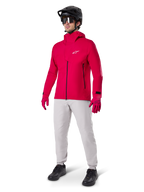 Modell iförd Alpinestars A-Dura Waterproof Pants i Titanium-grått, kombinerat med en klarröd vattentät jacka och matchande handskar, svart mountainbikehjälm med goggles och svarta skor, komplett mountainbikeutrustning för våta terrängförhållanden