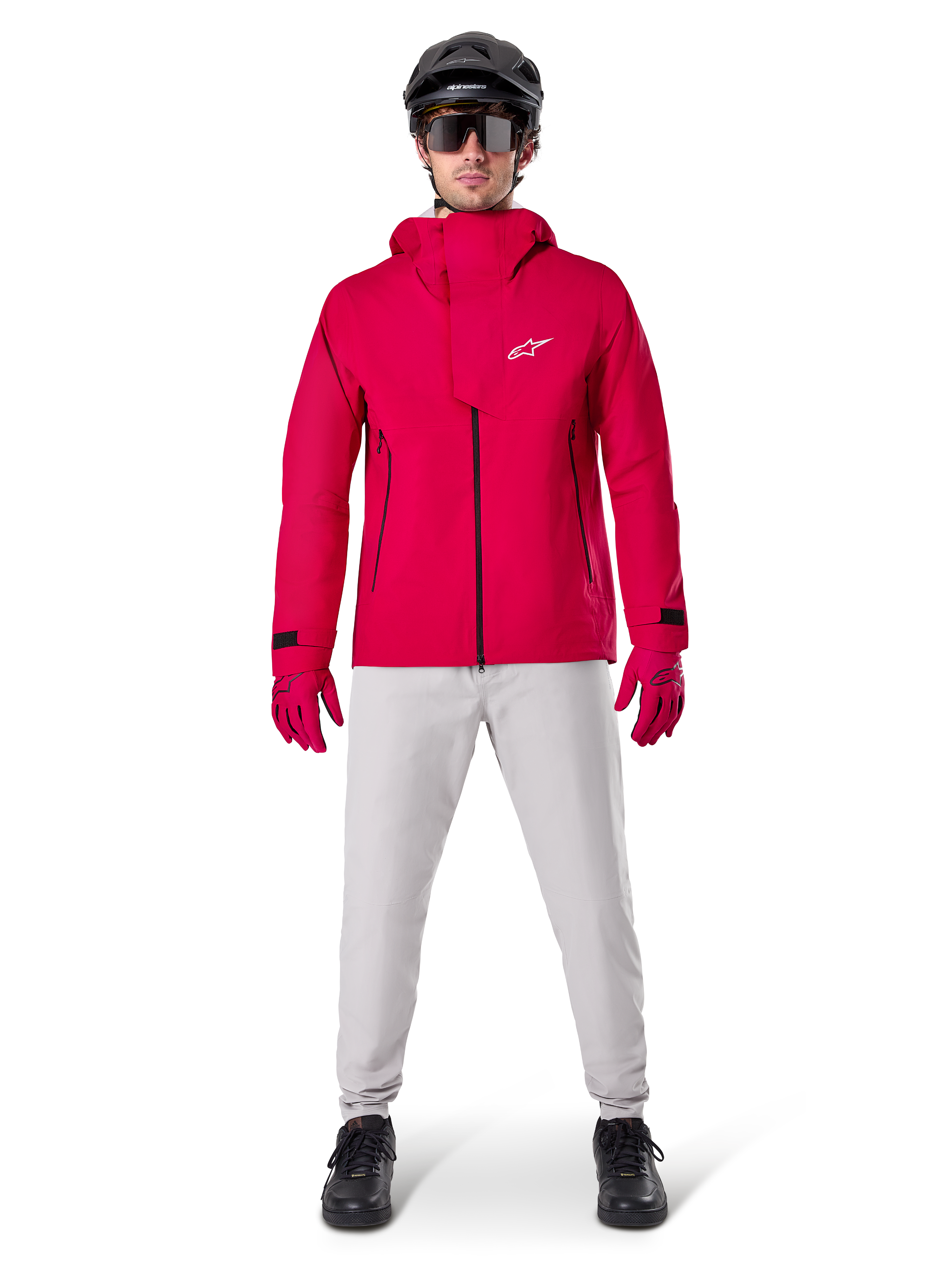 Alpinestars A-Dura Waterproof Pants, MTB-byxor, Titanium Gray, bärs med en starkröd jacka med huva, röda handskar och en svart mountainbikehjälm, professionell vattentät cykelutrustning för våta terrängförhållanden