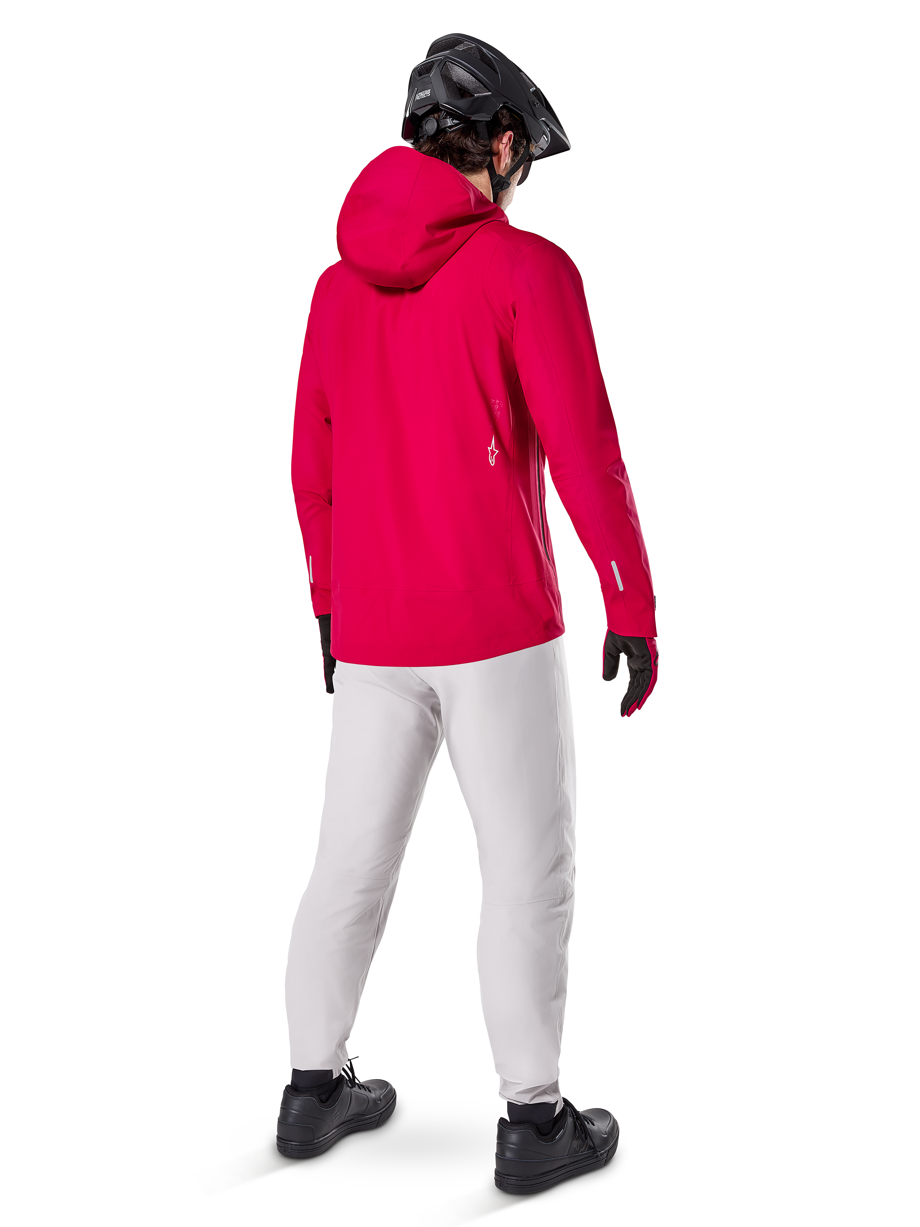 Alpinestars A-Dura Waterproof Pants i Titanium, bakifrån av en cyklist som bär de ljusgrå tekniska mountainbikebyxorna med en klarröd huvjacka och svart hjälm, slitstark vattentät utrustning för cykling i våta förhållanden