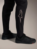 Svarta A-Supra Elite MTB-byxor med en silverfärgad Astars-logotyp på underbenet för högpresterande MTB-cykling.