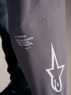 A-Supra Elite-byxor i faded gray med vit Alpinestars-branding och racing-mottot ”One Goal. One Vision.”
