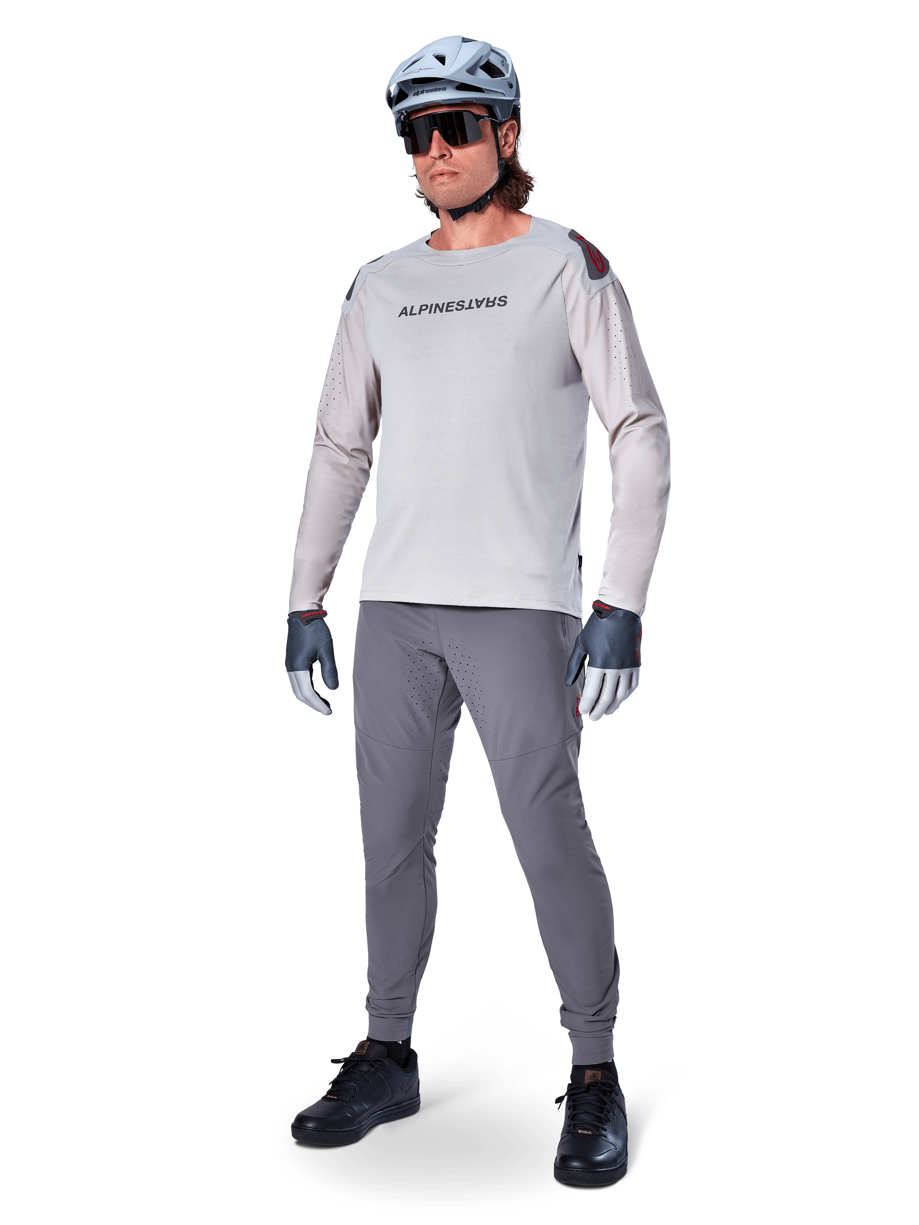 Alpinestars A-Aria Elite byxor, mörkgrå MTB-byxor, burna av en cyklist med en ljusgrå långärmad tröja och grå hjälm, med laserskuren ventilation på låren och en avsmalnande prestandapassform för mountainbikecykling.