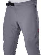 Alpinestars A-Aria Elite byxor, MTB-cykelbyxor, mörkgrå, närbild som visar magnetiskt spänne, blixtlåsförsedd sidoficka och laserskurna ventilationsperforeringar på innerlåren för prestanda vid trailcykling