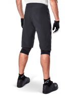 Alpinestars A-Aria Shorts, mountainbikeshorts, svarta, baksida som visar prestandapassform och stilren design, bärs med svarta handskar och strumpor med vit Astars-logotyp, teknisk cykelutrustning för terrängkörning