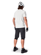 Mountainbikecyklist bakifrån bärande Alpinestars A-Aria Shorts i svart, vit kortärmad funktionströja, vit hjälm, svarta handskar och svarta mountainbikeskor, cykelutrustning för stigcykling
