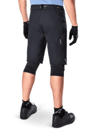 Alpinestars A-Dura Elite Shorts, Black, rear view of a rider wearing mountain bike gear including black knee pads, gloves, and socks with white logos, featuring zippered side pockets and reflective accents on a durable Cordura fabric.