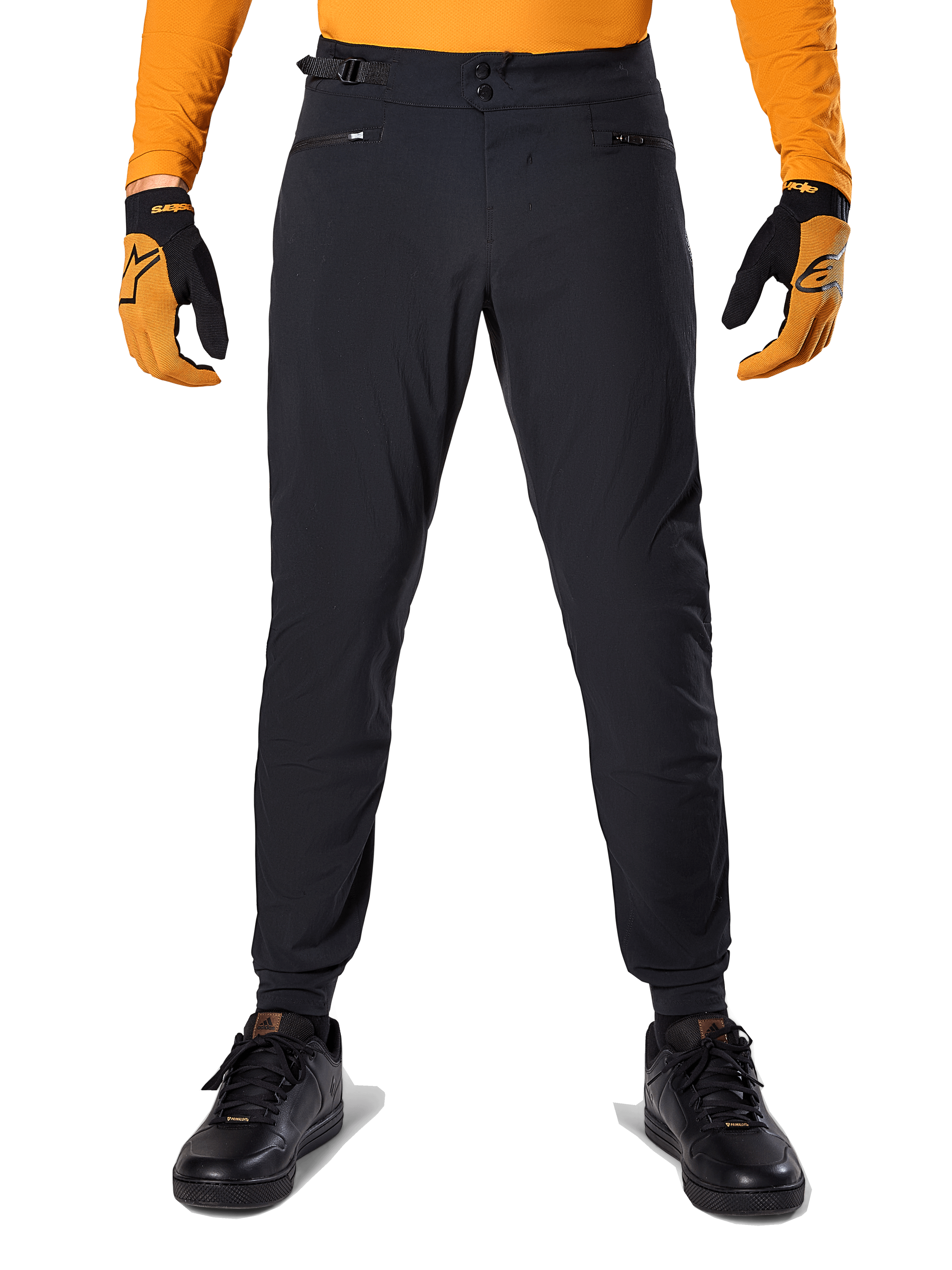 Alpinestars A-Dura-byxor, MTB-byxor, svarta, bärs med en orange långärmad tröja och svart-orangea handskar, med dubbel tryckknappsstängning och sidojustering i midjan, slitstarkt textilmaterial för terrängcykling
