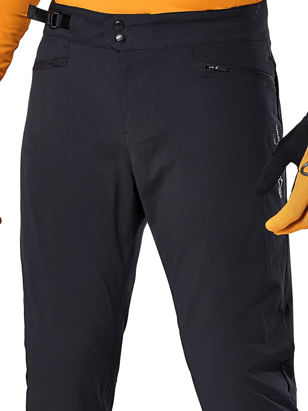 Alpinestars A-Dura Pants, svarta MTB-cykelbyxor, närbild med dubbel tryckknappsstängning i midjan, justerbar sidostängning och blixtlåsförsedda fickor, matchade med en orange tröja och handskar