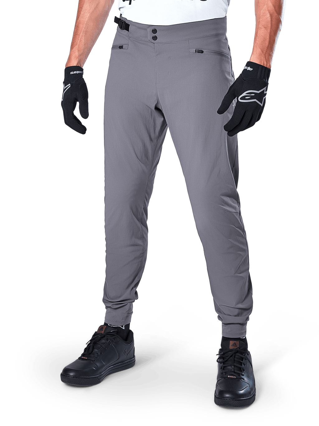 Alpinestars A-Dura Pants, mörkgrå MTB-byxor med dubbel tryckknappsstängning och blixtlåsförsedda fickor, elastiska muddar, bärs med svarta cykelhandskar och svarta sneakers
