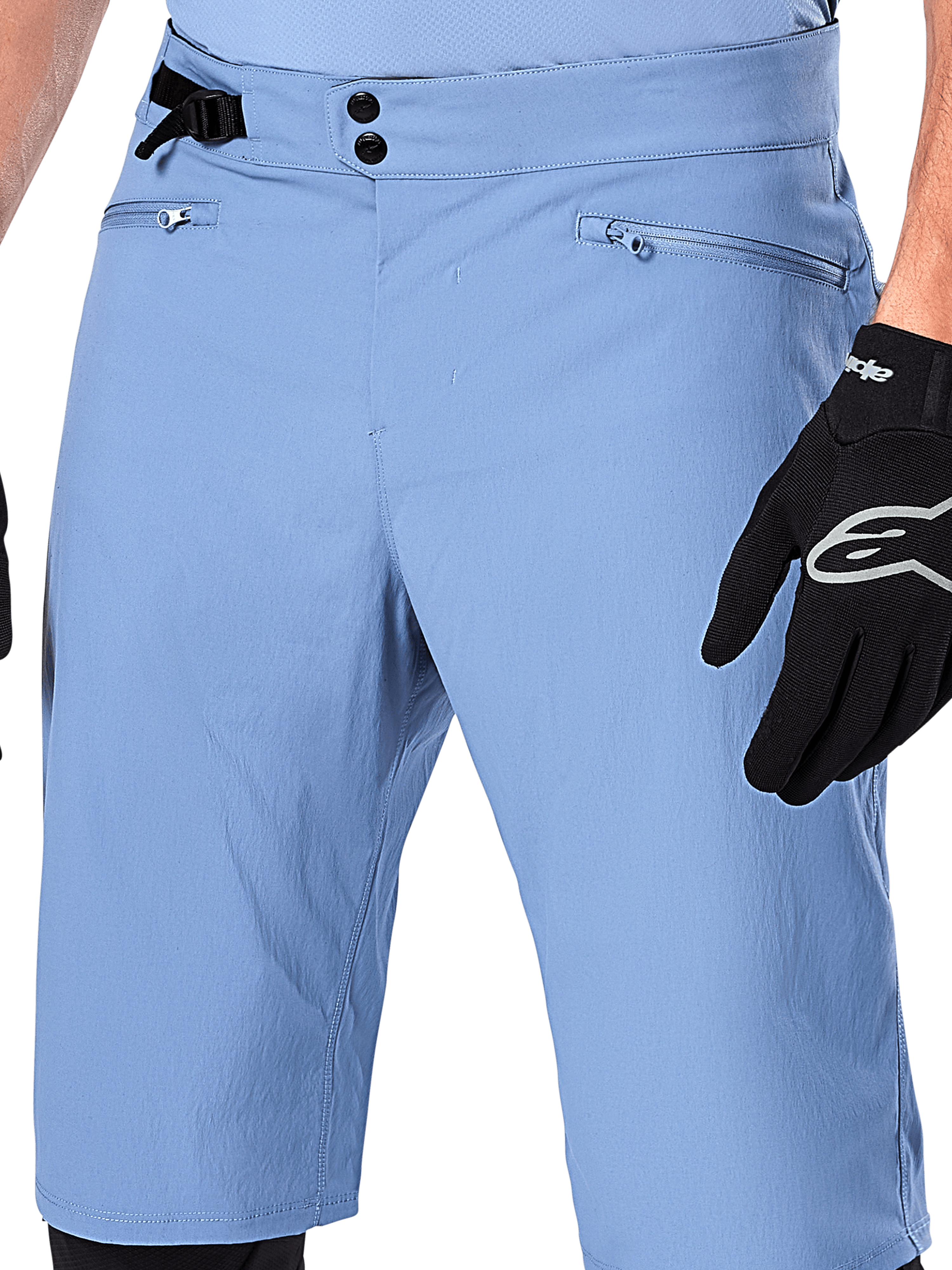 Alpinestars A-Dura Shorts, Infinity Blue mountainbikeshorts, närbild på midjan med dubbelknäppning, justerbart sidoreglage och dragkedjeförsedda nätfodrade fickor, bärs med en svart Alpinestars-handske