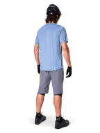 Alpinestars A-Dura Shorts, mörkgrå MTB-shorts, sedda bakifrån, bärs med en ljusblå kortärmad tröja och svart mountainbikehjälm, svarta handskar och strumpor med svarta skor, funktionell och slitstark utrustning för terrängcykling