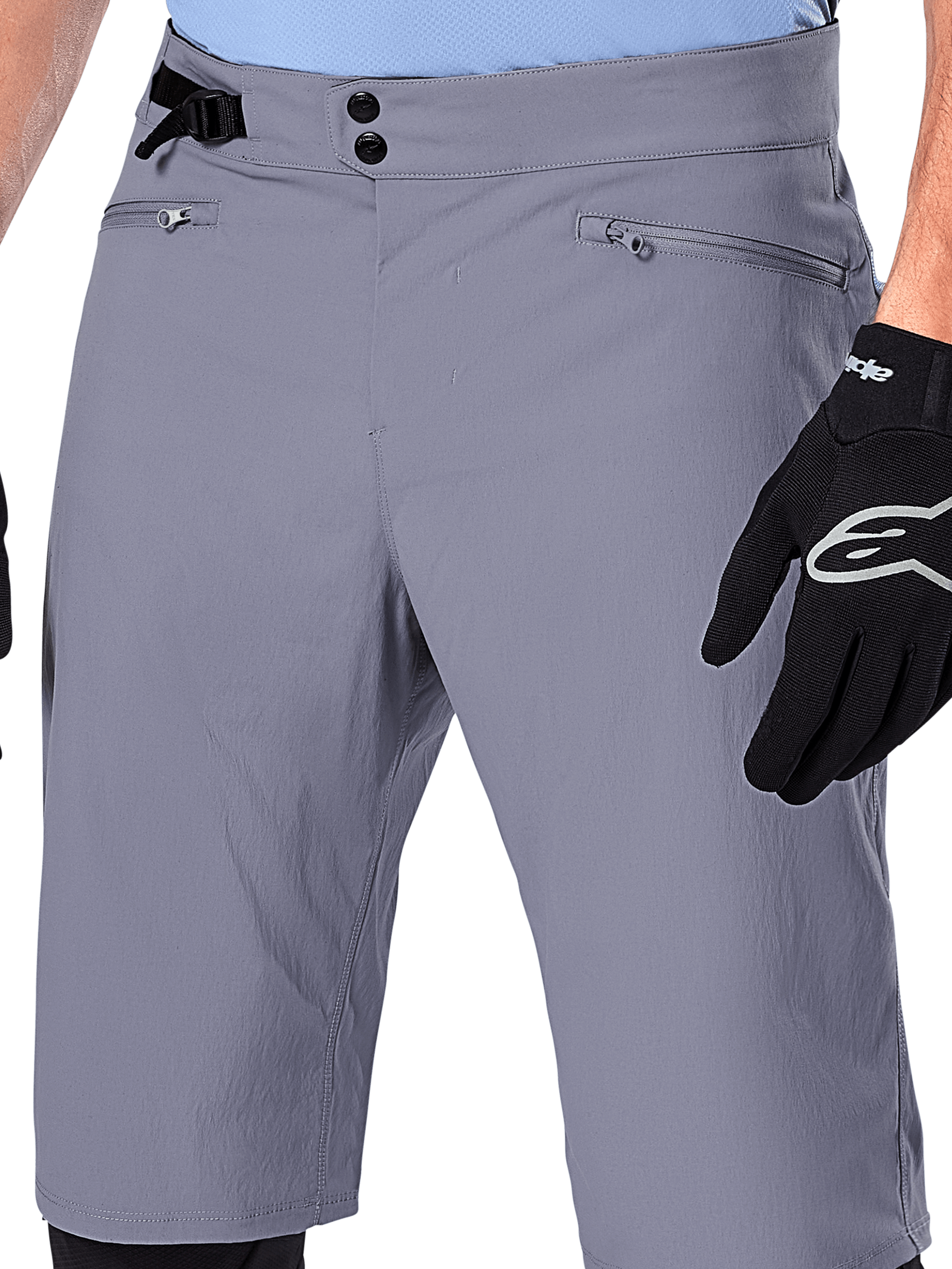 Alpinestars A-Dura Shorts, MTB-shorts, mörkgrå, närbild på midjan som visar dubbla tryckknappar, sidoreglage och dragkedjeförsedda fickor, kombinerat med svarta cykelhandskar, slitstarka mountainbikekläder.