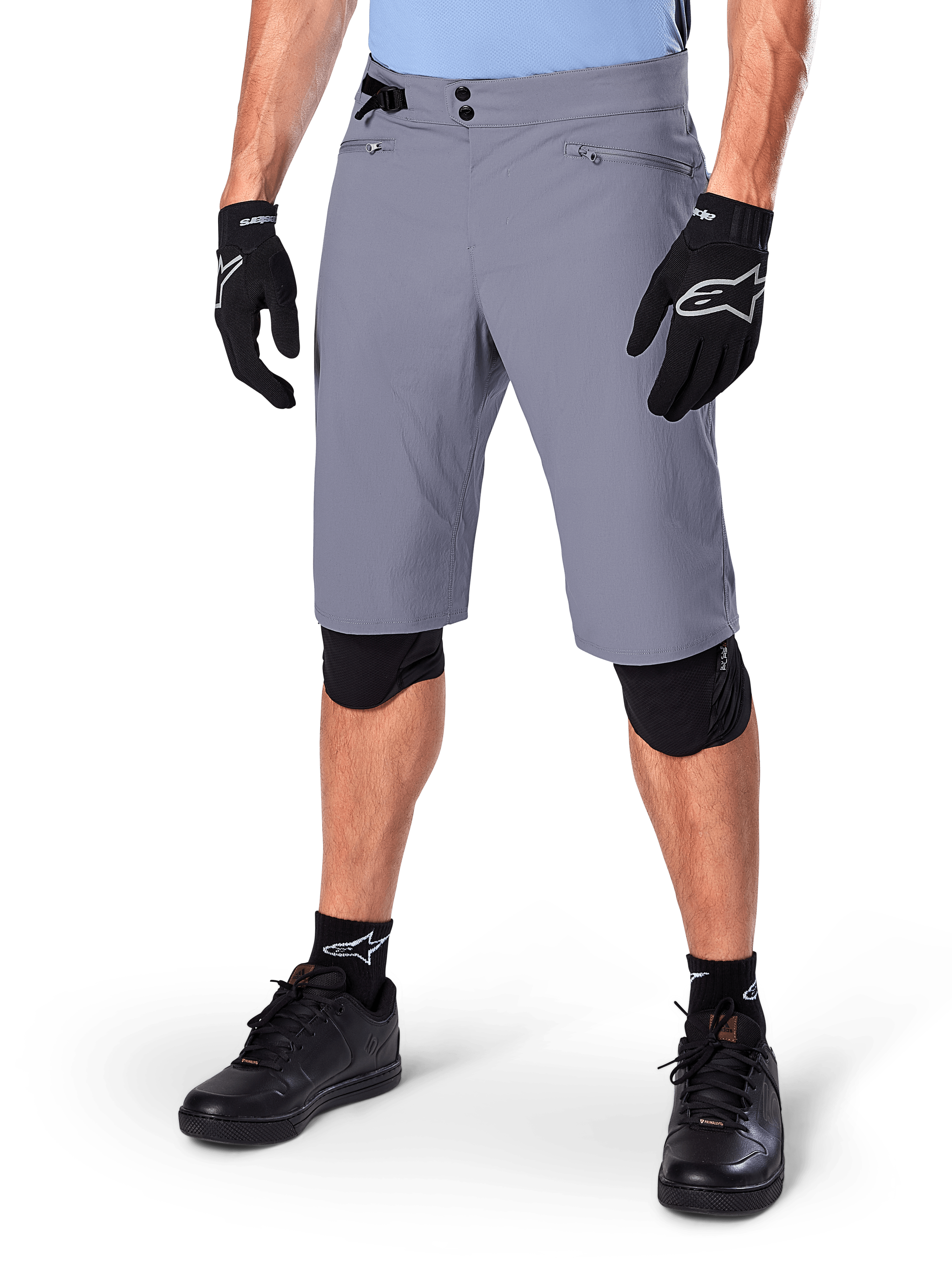 Alpinestars A-Dura Shorts, mörkgrå mountainbikeshorts, matchade med svarta handskar och knäskydd, med dragkedjeförsedda fickor och dubbel tryckknappsstängning, robust cykelutrustning för terrängkörning