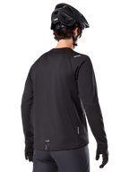 Alpinestars A-Dura Thermal Tröja, långärmad mountainbiketröja, svart, vy bakifrån som visar förlängt bakstycke, små reflekterande detaljer och logotyp vid fållen, bärs med svart hjälm och handskar för cykling i kallt väder