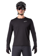 Alpinestars A-Dura Thermal Tröja, svart långärmad mountainbike-tröja, bärs med en svart hjälm och stora solglasögon, liten vit Alpinestars-logotyp på bröstet, normal passform, MTB-cykelkläder
