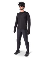 Modell som bär Alpinestars A-Dura Thermal Tröja, svart långärmad MTB-tröja, svart mountainbikehjälm, solglasögon och mörkgrå byxor, med en liten vit logotyp på bröstet, isolerande fleecekonstruktion för cykling i kallt väder