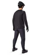 Alpinestars A-Dura Thermal Tröja, långärmad cykeltröja för herrar, svart, vy bakifrån på modell med svart MTB-hjälm, mörkgrå byxor och svarta handskar, professionella mountainbike-kläder för kallt väder