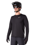Alpinestars A-Dura Thermal Jersey, svart långärmad mountainbiketröja, vit logotyp på bröstet, bärs med svart hjälm och handskar, stilren sportig design för trailcykling