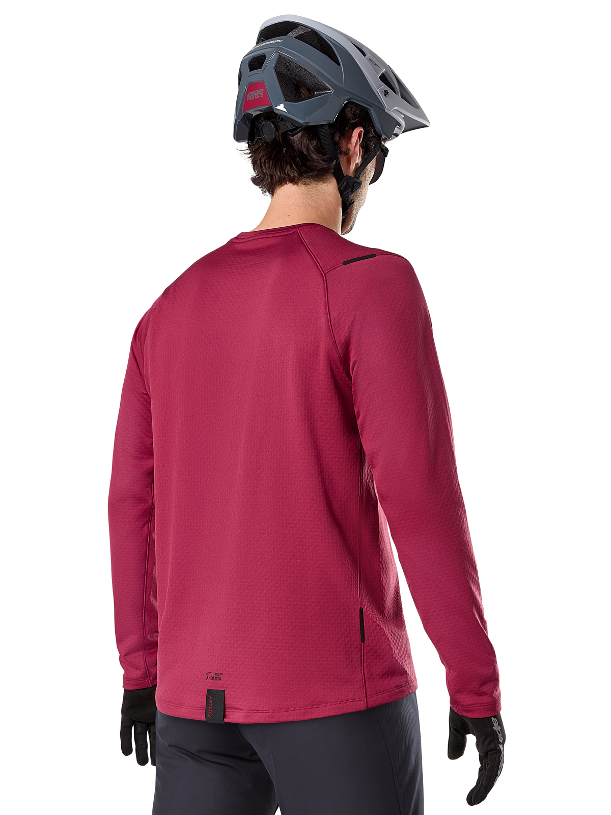 Alpinestars A-Dura Thermal Jersey, långärmad mountainbiketröja, vinröd, baksida på modell med grå MTB-hjälm och svarta handskar, förlängt ryggparti och små logotypdetaljer, designad för trailcykling i kallt väder