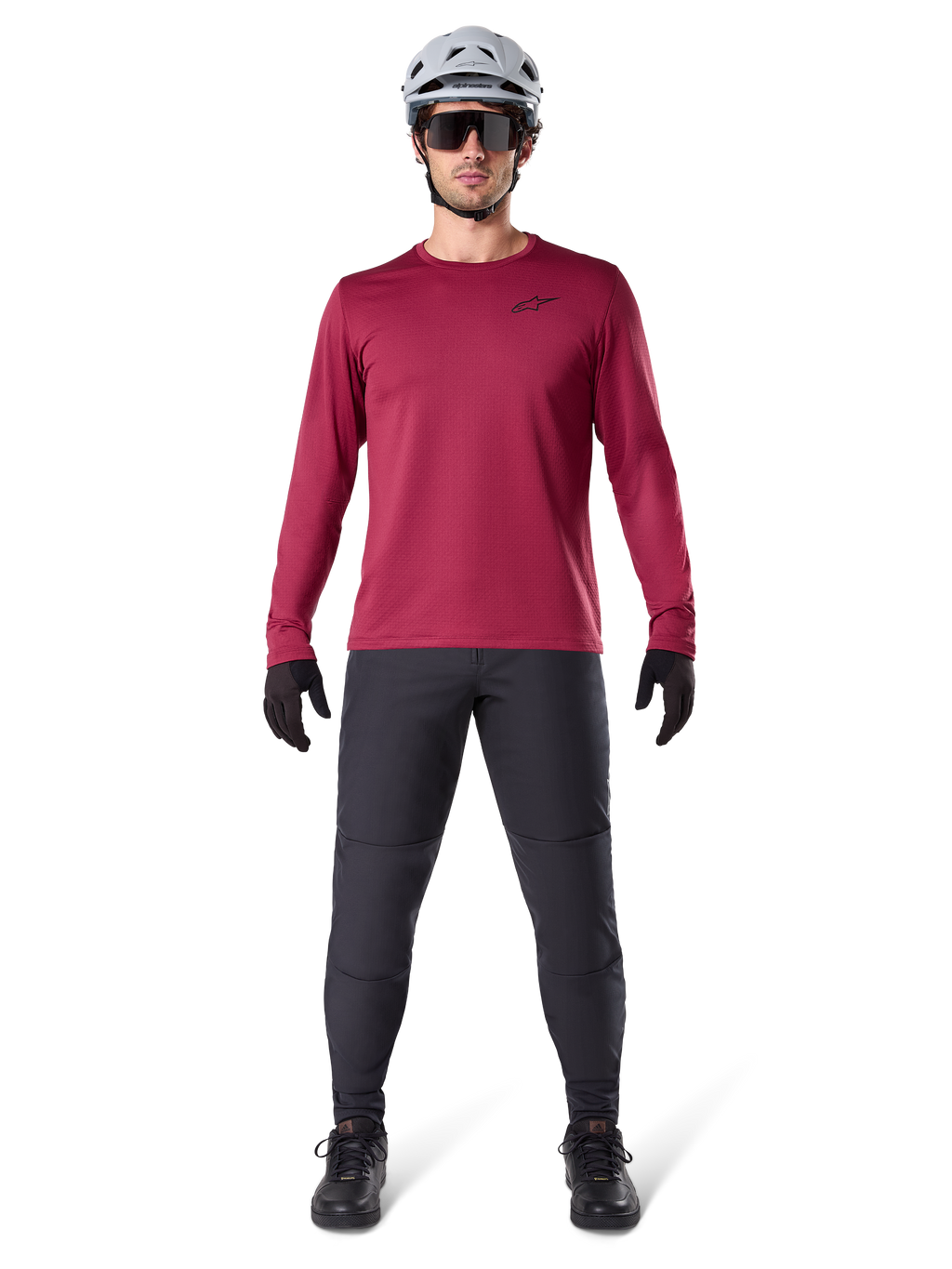 Manlig modell som bär Alpinestars A-Dura Thermal Jersey i vinrött, långärmad isolerad cykeltröja, kombinerad med mörkgrå mountainbikebyxor, vit hjälm, svarta solglasögon och svarta handskar, professionell MTB-utrustning för kallt väder