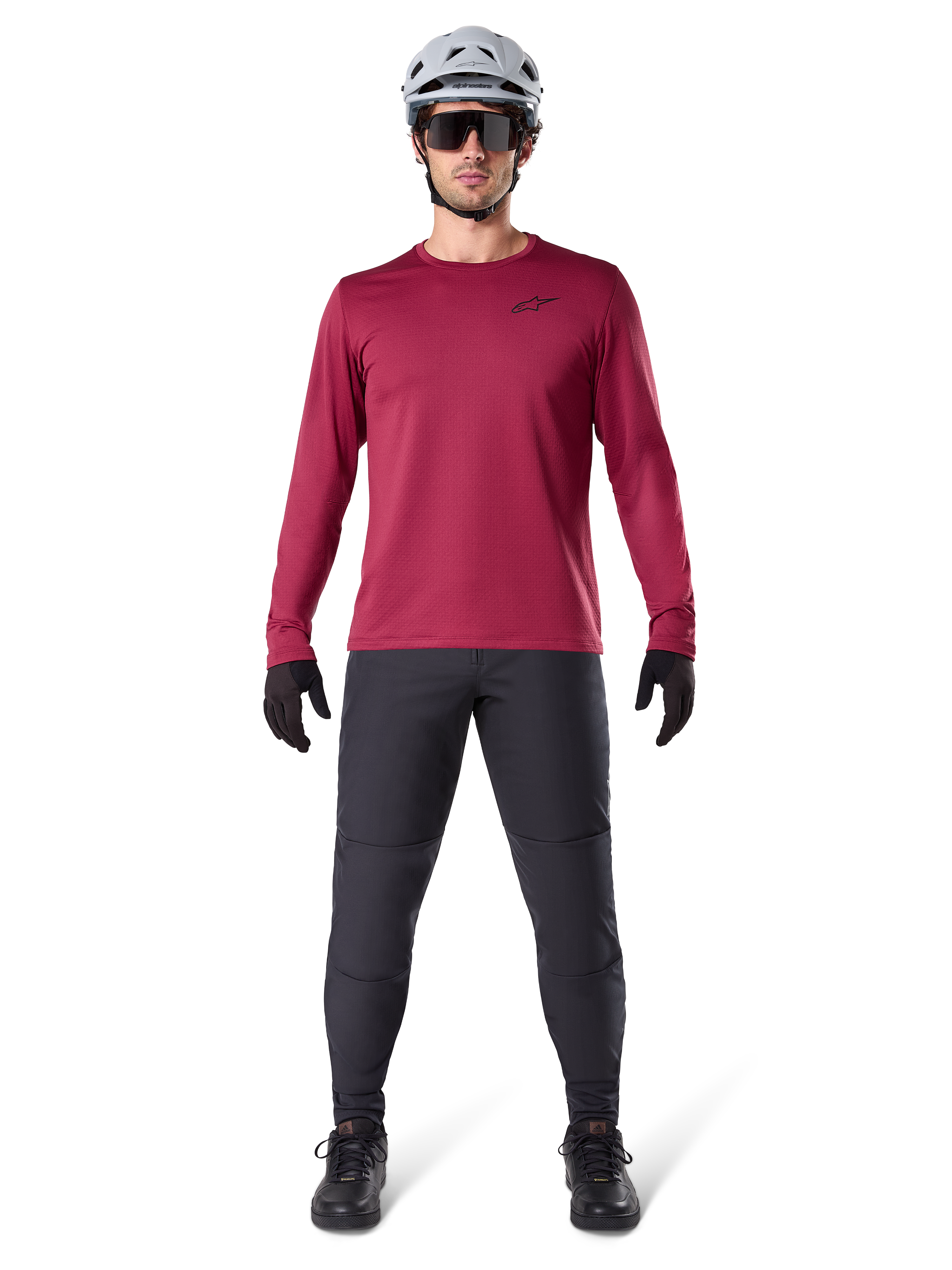 Manlig modell som bär Alpinestars A-Dura Thermal Jersey i vinrött, långärmad isolerad cykeltröja, kombinerad med mörkgrå mountainbikebyxor, vit hjälm, svarta solglasögon och svarta handskar, professionell MTB-utrustning för kallt väder