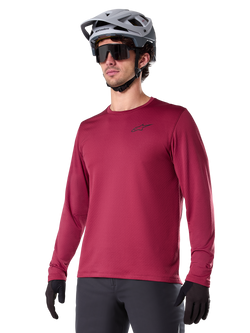 Alpinestars A-Dura Thermal Jersey, Long-Sleeve Mountain Biking Jersey, Burgundy Red, featuring insulated fleece lining and small black chest logo, worn with a gray helmet, black sunglasses, and black gloves, designed for cold-weather cycling
