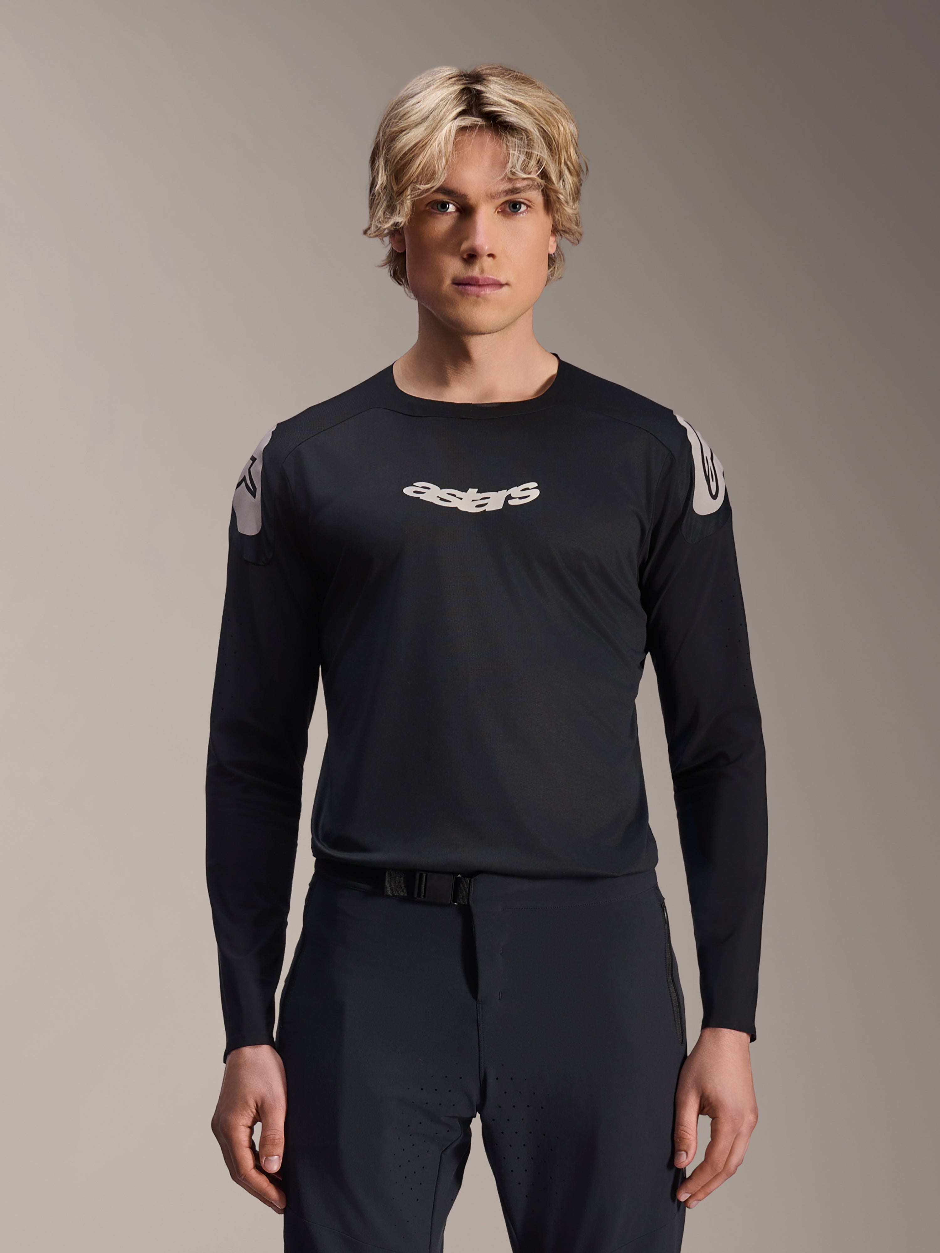 Alpinestars A-Aria Polartec Elite-tröja, långärmad MTB-tröja, svart, med vit ”astars”-logotyp på bröstet och vit axelgrafik, teknisk cykelutrustning buren av en modell