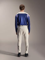 Alpinestars A-Aria Polartec Maker Elite långärmad tröja, Baja Blue och off-white, sedd bakifrån på modell som bär teknisk mountainbike-utrustning inklusive off-white byxor med Alpinestars-logotyp på underbenen, prestandaorienterad cykeloutfit för terräng