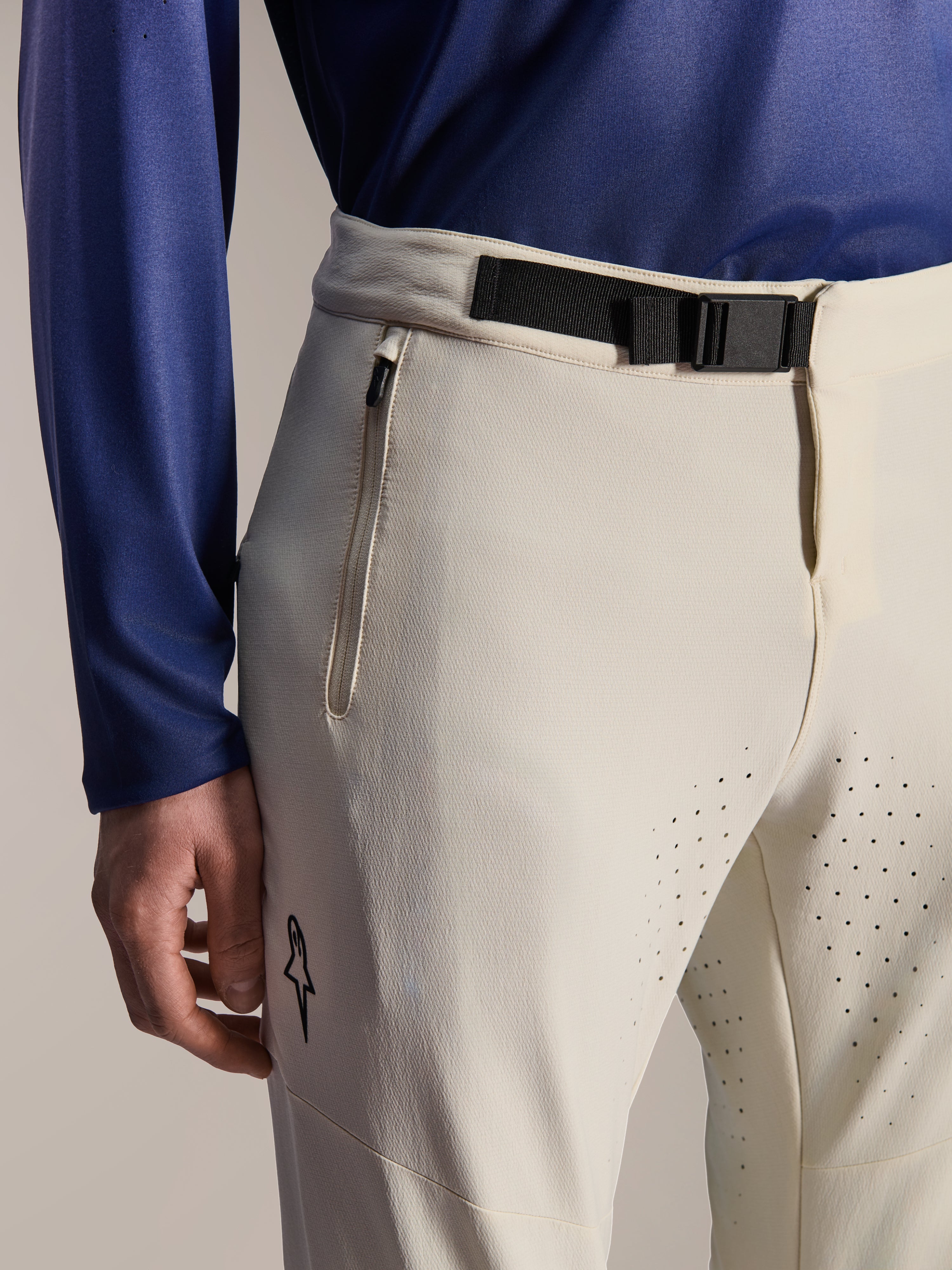 Alpinestars A-Aria Elite-byxor, mountainbikebyxor, Ecru, närbild med svart magnetiskt midjespänne, blixtlåsförsedd ficka och laserskurna ventilationshål, prestandautrustning för terrängcykling