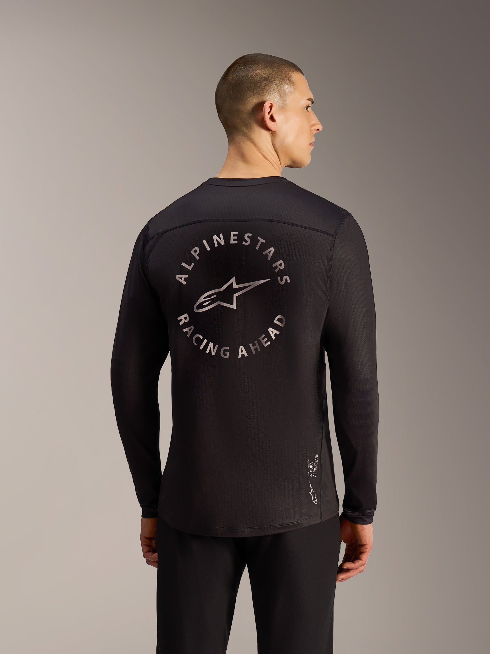 Svart Alpinestars A-Dura Air långärmad tröja, ryggvy med cirkulär Racing Ahead-grafik och ventilerande mesh-tyg.