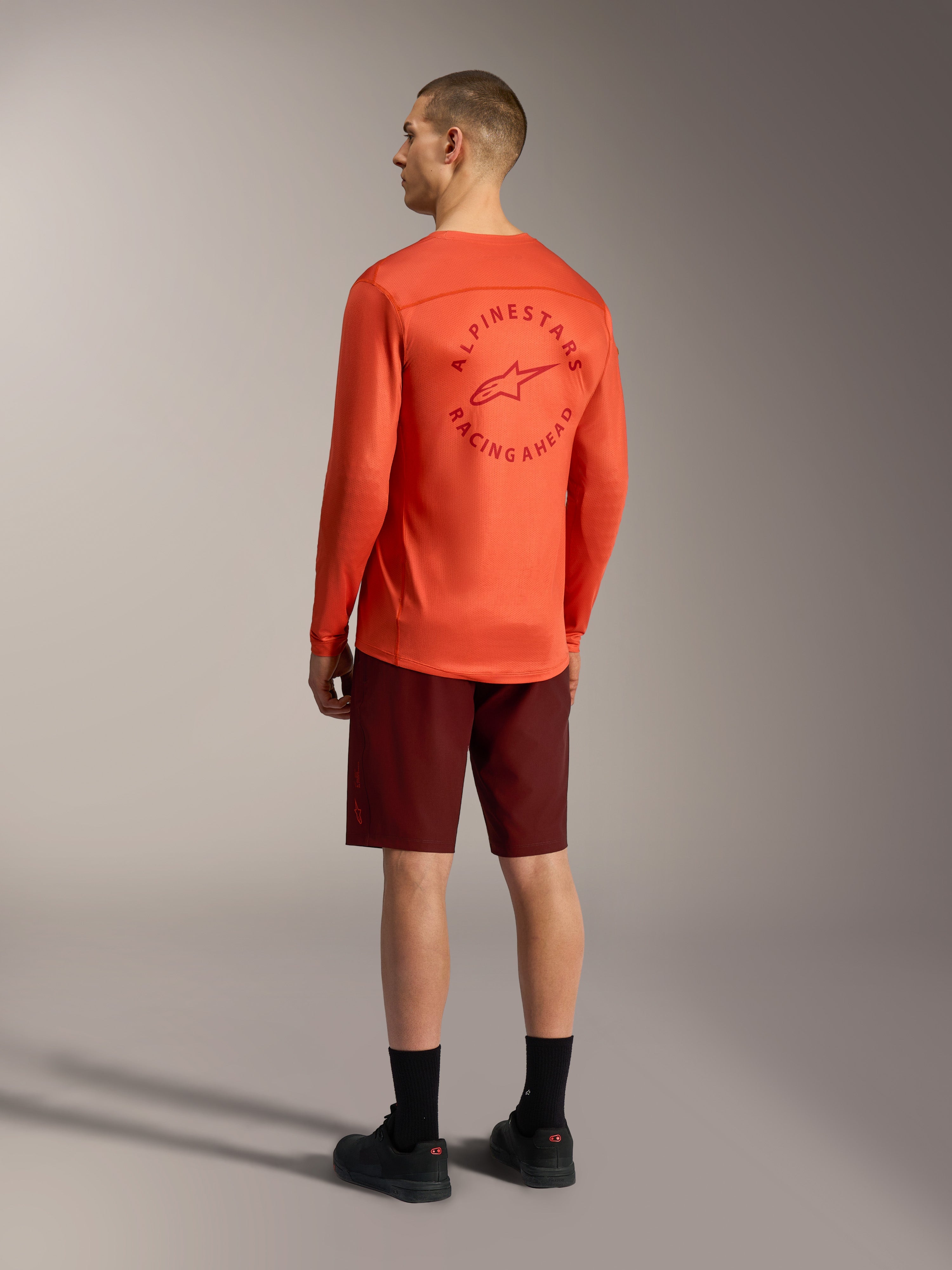 Alpinestars A-Dura Ride Shorts in Bordeaux and bright orange A-Dura Air LS Jersey, rear view of mountain bike gear.