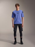Alpinestars A-Aria Elite Shorts, MTB-shorts, Black Titanium, bärs med blå kortärmad tröja, knäskydd och svarta cykelskor, helkroppsbild i studio, prestandakläder för mountainbike