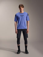 Alpinestars A-Aria Elite Shorts, MTB-shorts, Black Titanium, bärs med blå kortärmad tröja, knäskydd och svarta cykelskor, helkroppsbild i studio, prestandakläder för mountainbike