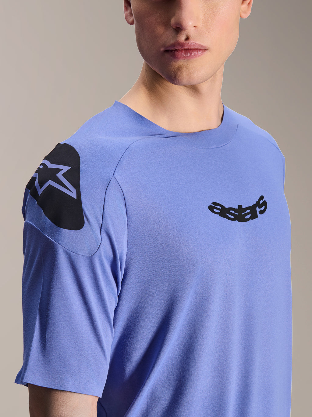 Alpinestars A-Aria Polartec Elite-tröja, kortärmad mountainbiketröja, Baja Blue, närbild av bröst och axel med svart astars-logotyp och axelgrafik, tekniskt fukttransporterande material för terrängcykling
