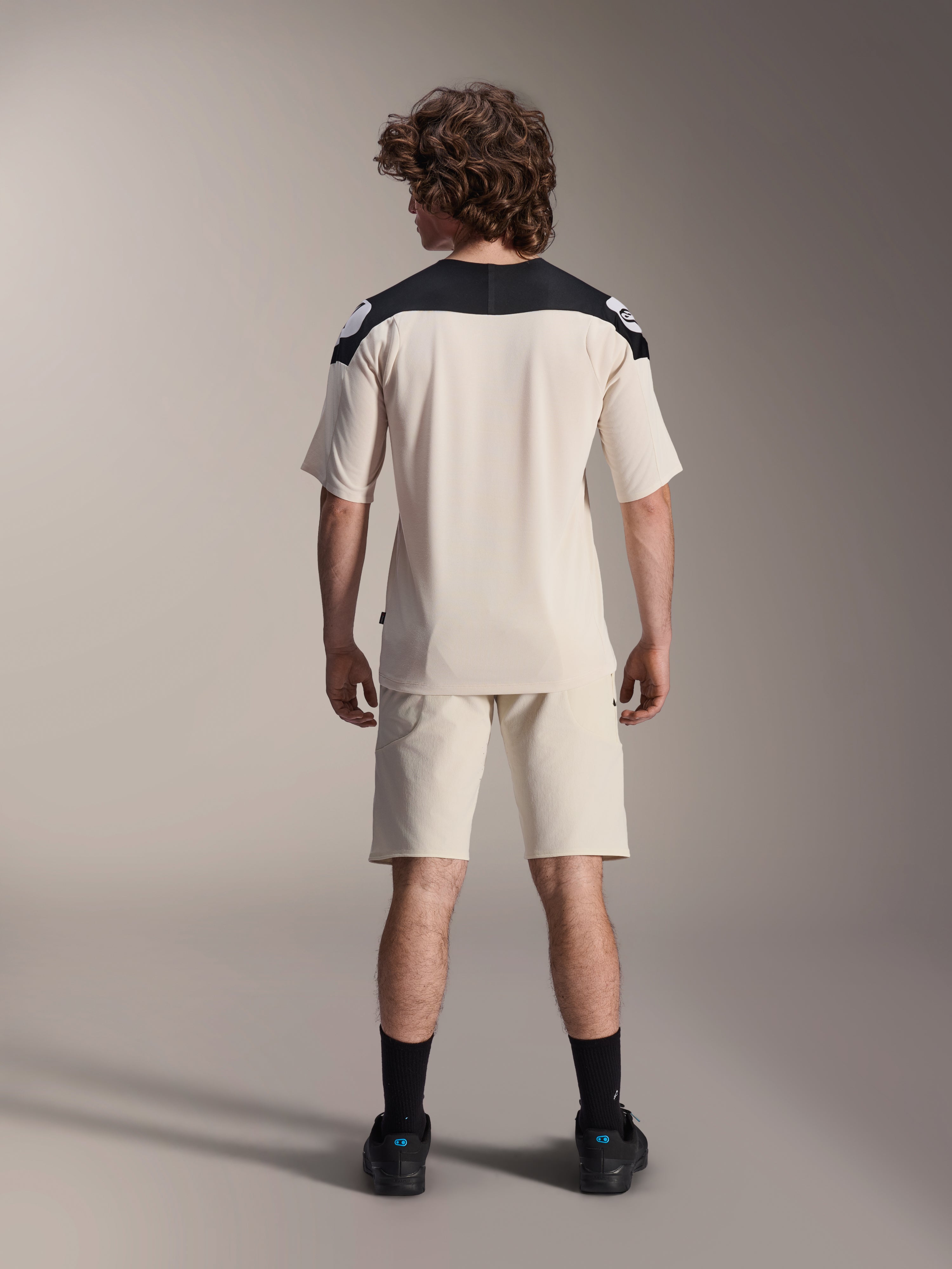 Alpinestars A-Aria Elite Shorts och A-Aria Polartec Elite SS Jersey, Ecru med svarta axelpartier, ryggvy av en modell i mountainbike-utrustning, stylad med svarta strumpor och skor