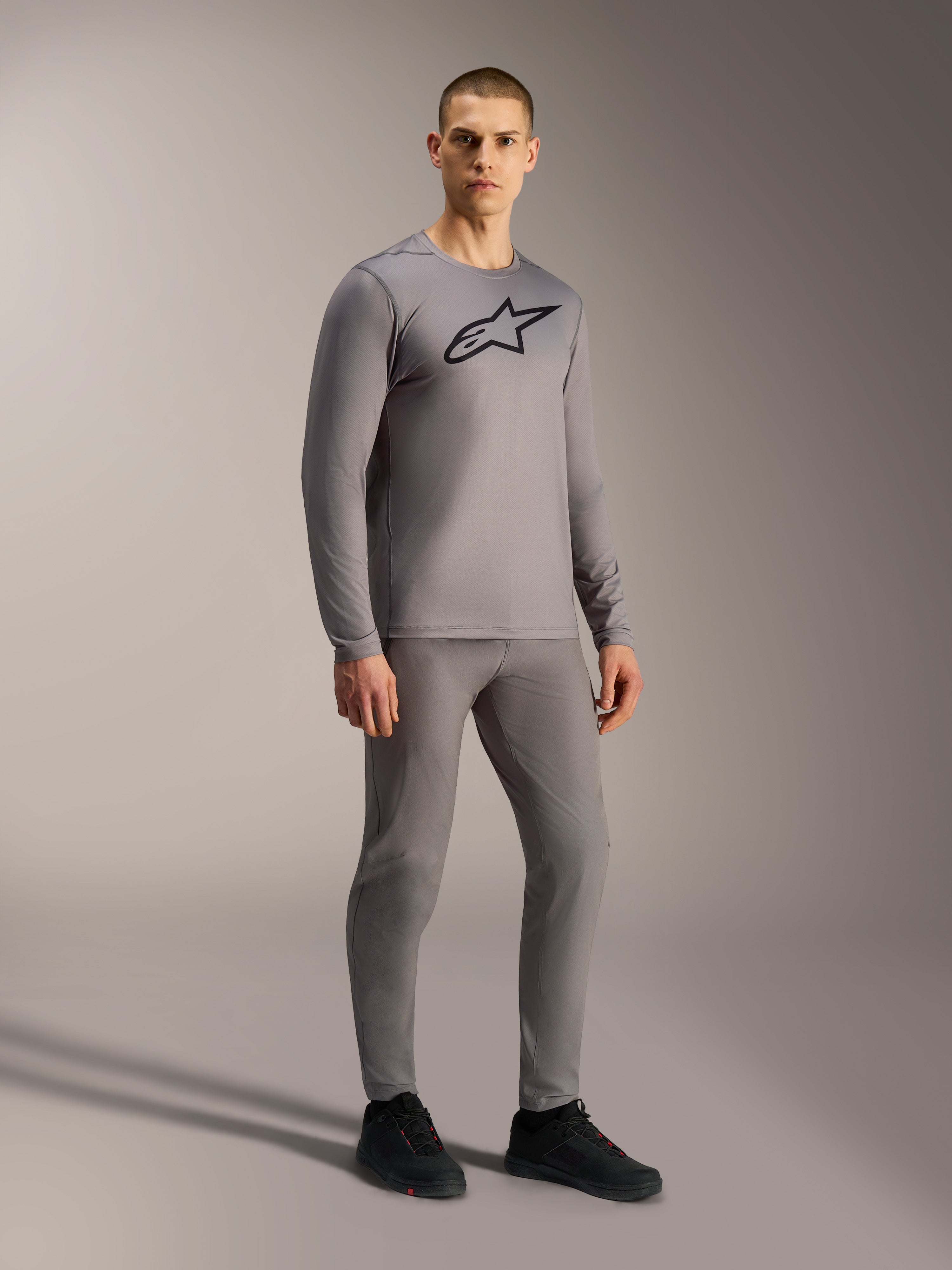 Grå A-Dura Ride långärmad tröja med svart bröstlogotyp, stylad på modell för en komplett mountainbike-look.