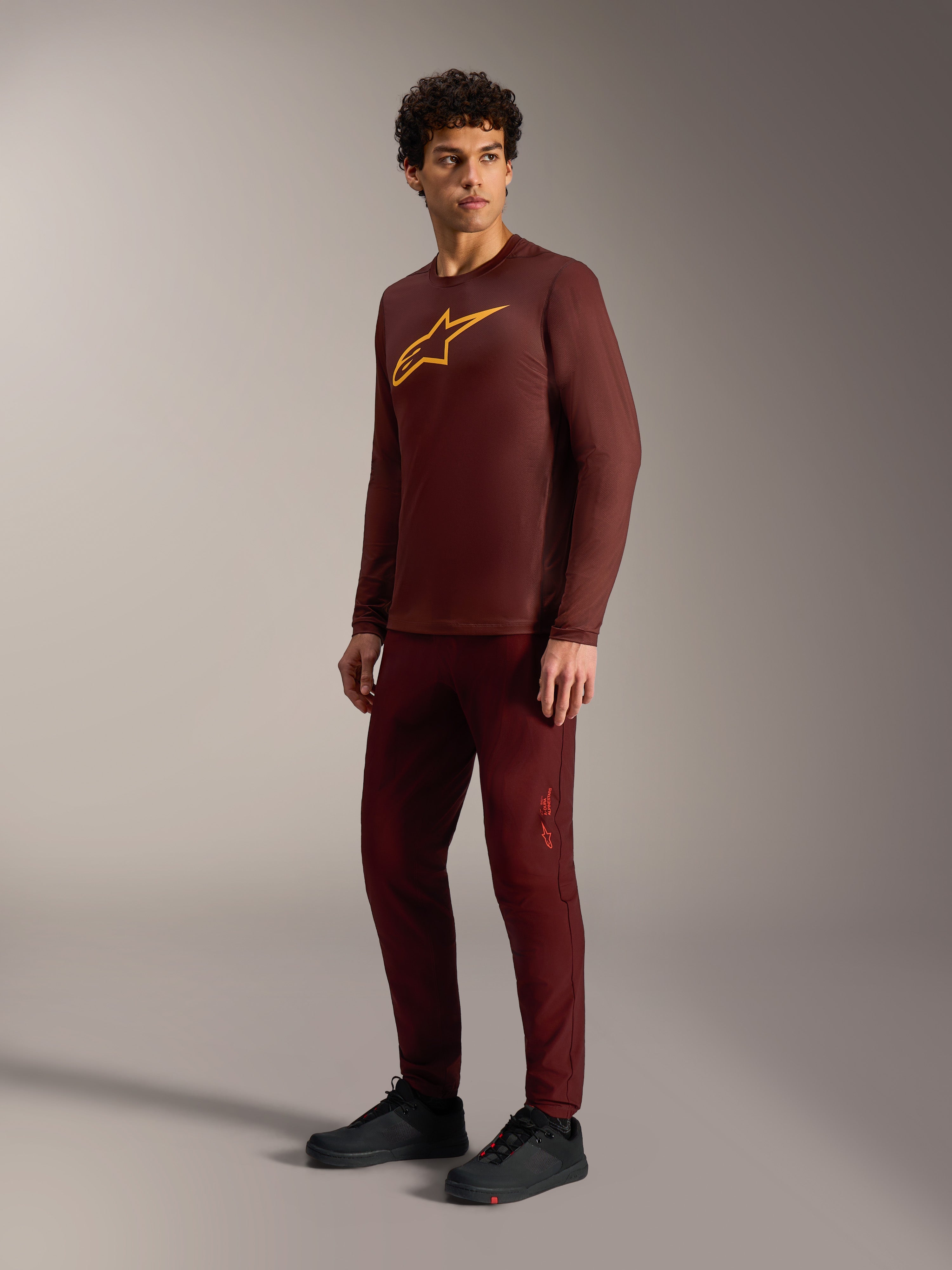 Bordeaux A-Dura Ride Long Sleeve Jersey with yellow Astars logo, styled with matching pants and black cycling shoes.