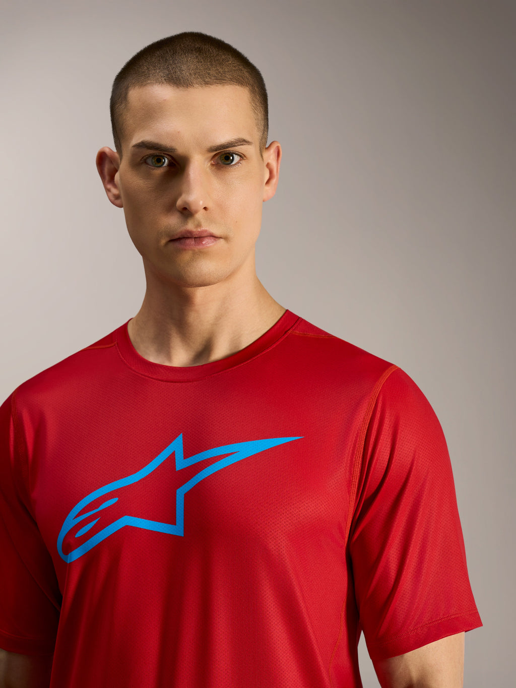 Alpinestars A-Dura Ride kortärmad tröja i rött med en blå logotyp, tekniska funktionskläder för MTB-stigar.
