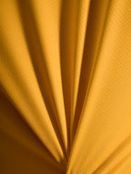 Närbild på tygstrukturen hos orange A-Dura Ride-tröja i lätt jacquardvävt poly/spandex-material.