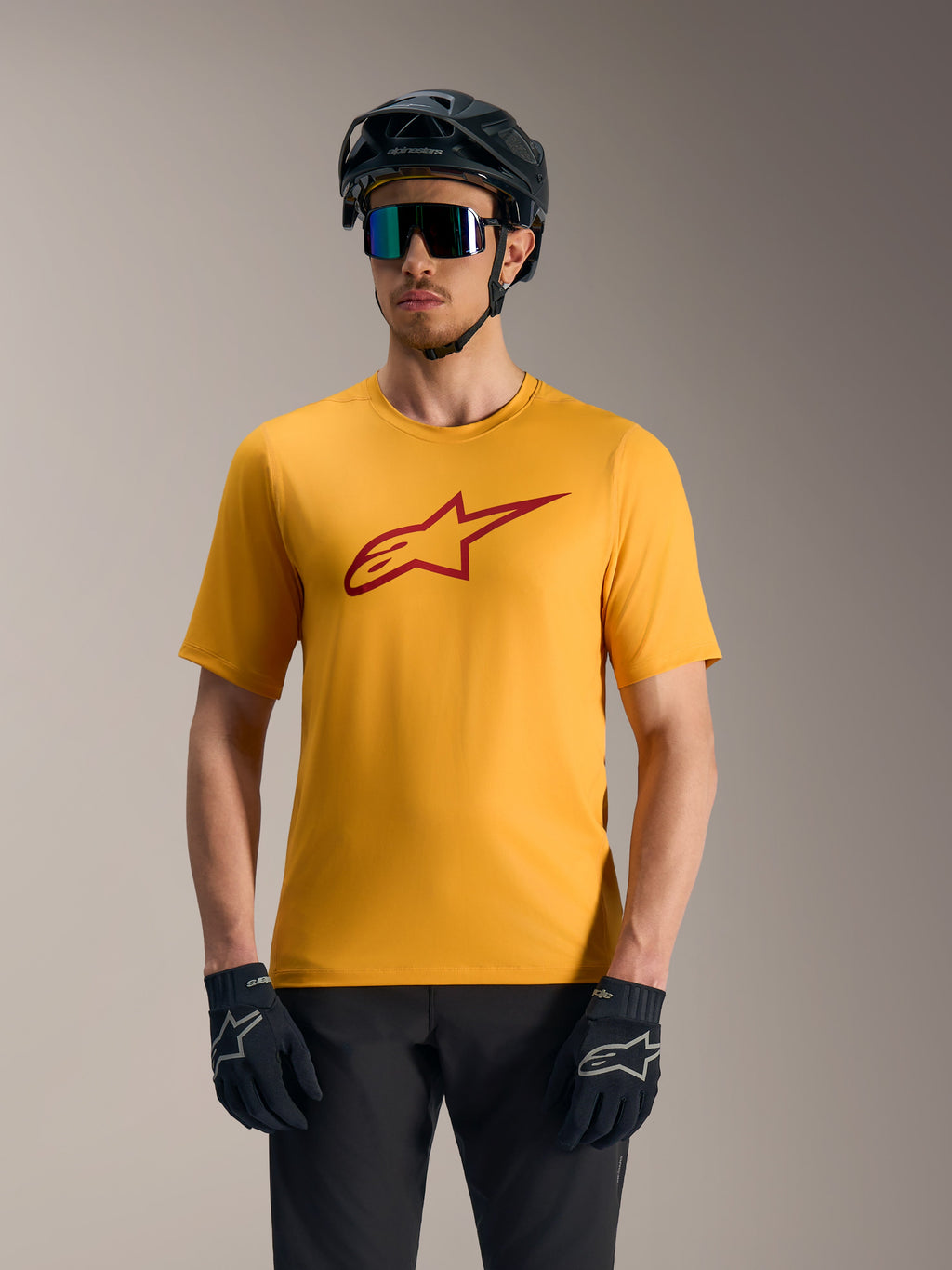Orange A-Dura Ride kortärmad tröja med röd Astars-logotyp, matchad med mountainbike-hjälm och handskar.