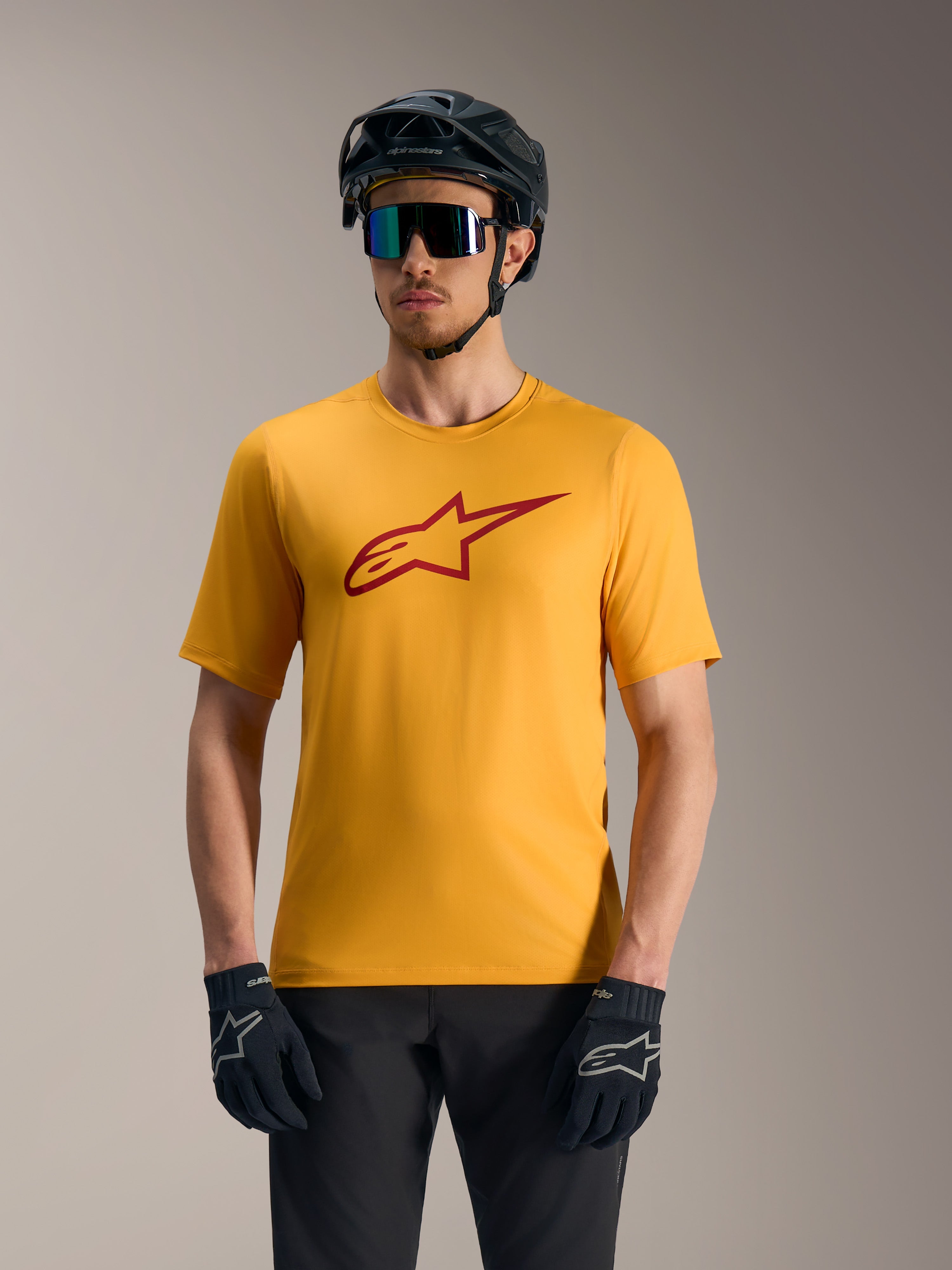 Orange A-Dura Ride kortärmad tröja med röd Astars-logotyp, matchad med mountainbike-hjälm och handskar.