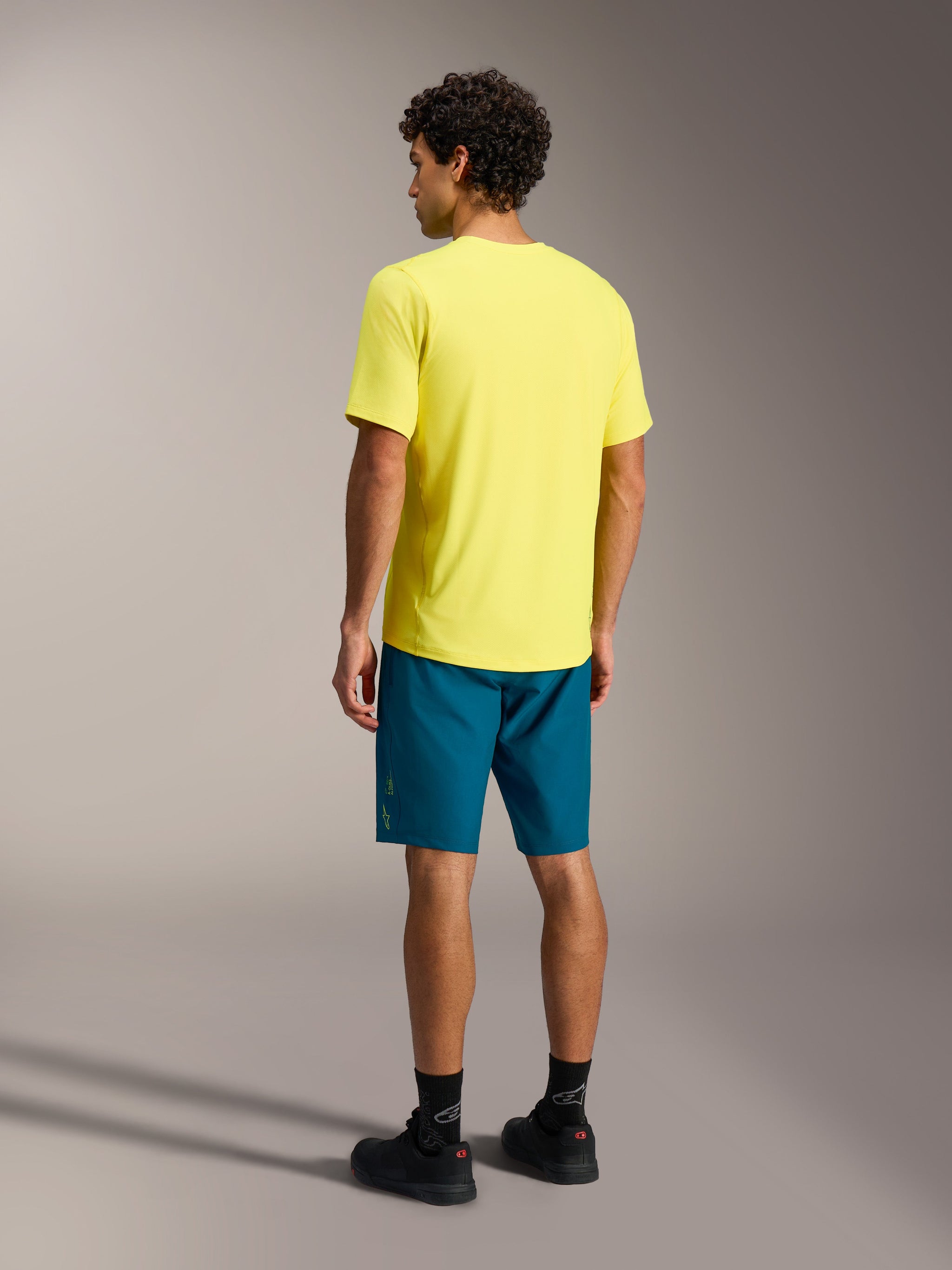 Yellow A-Dura Ride SS Jersey and blue green A-Dura Ride Shorts, Alpinestars mountain bike apparel shown from the rear.