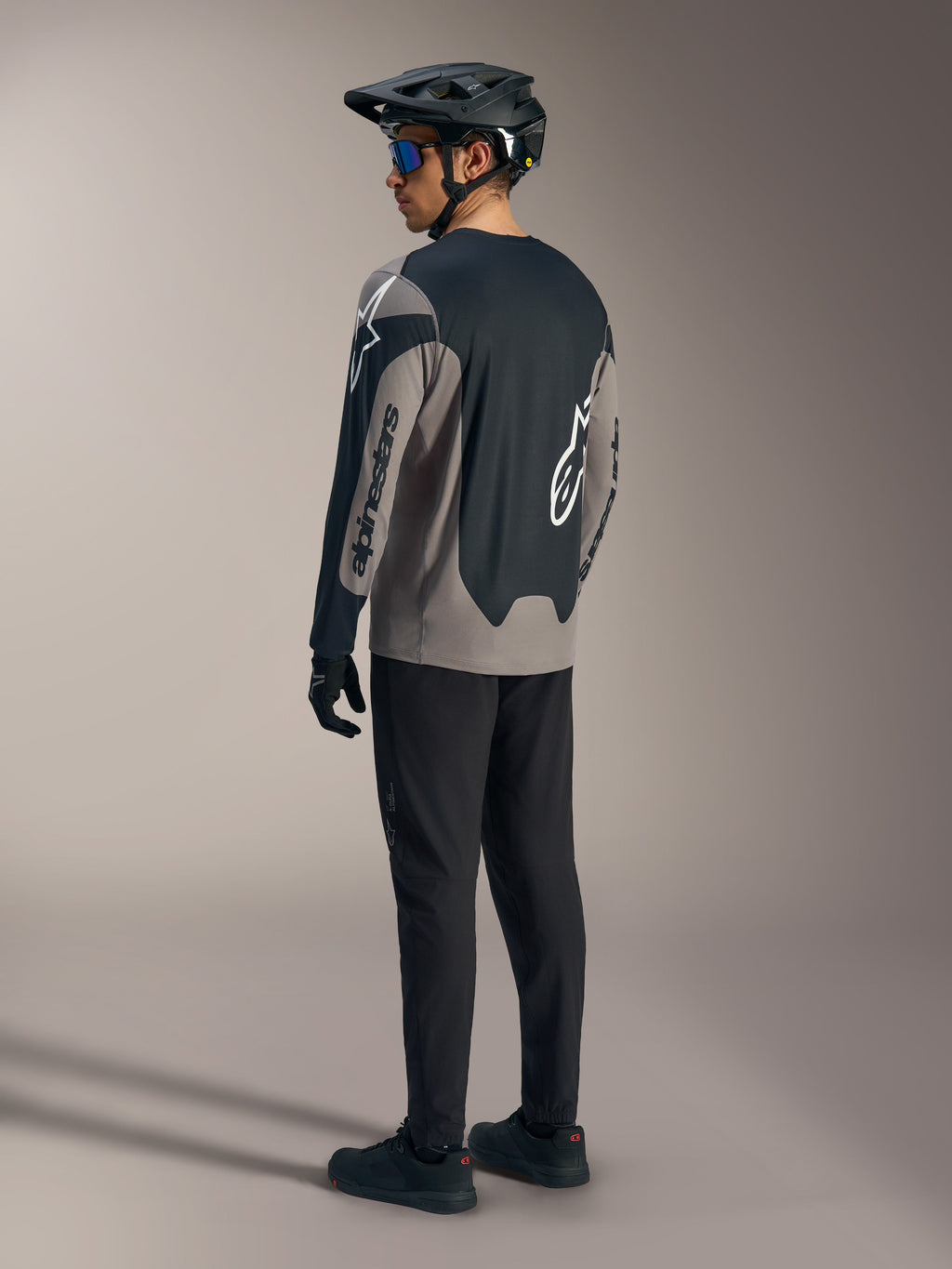 Grå och svart A-Dura Race långärmad tröja med Alpinestars-logotyper, sedd bakifrån i en komplett MTB-outfit.