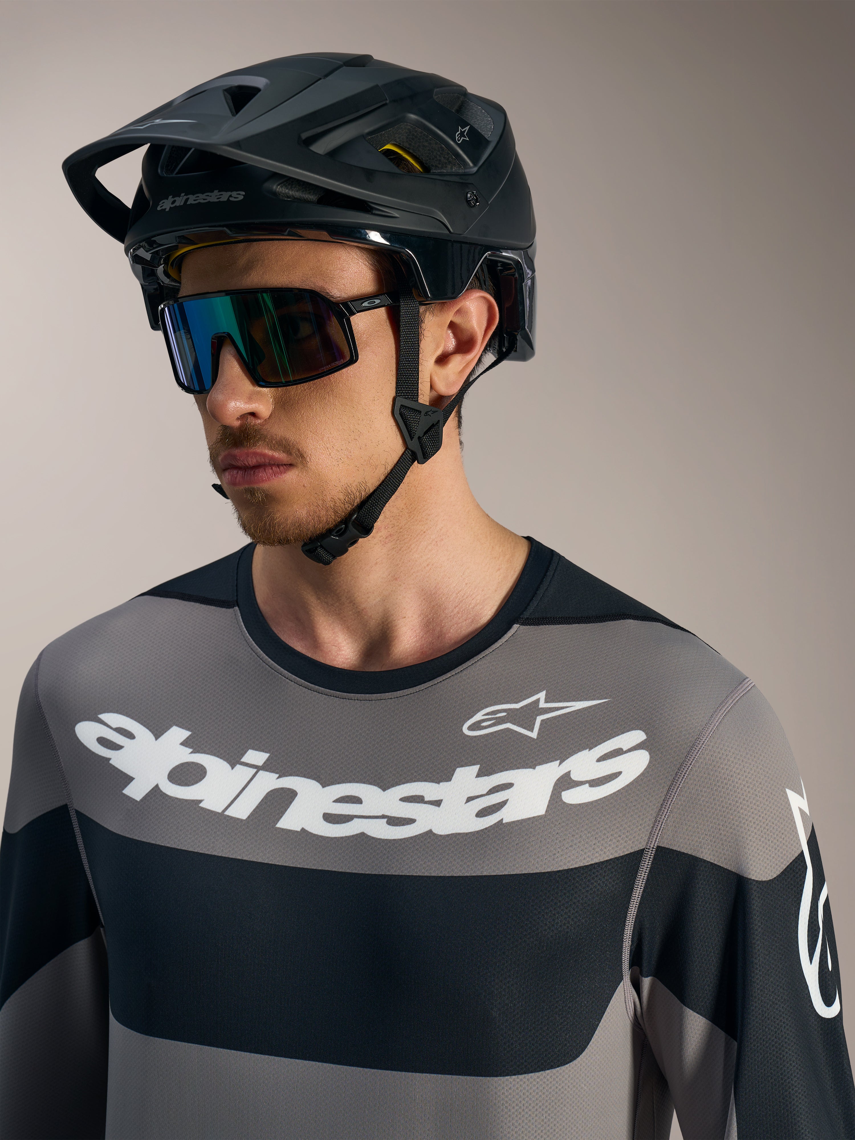 Alpinestars A-Dura Race långärmad tröja i grått med vita logotyper, svart MTB-hjälm och sportglasögon.