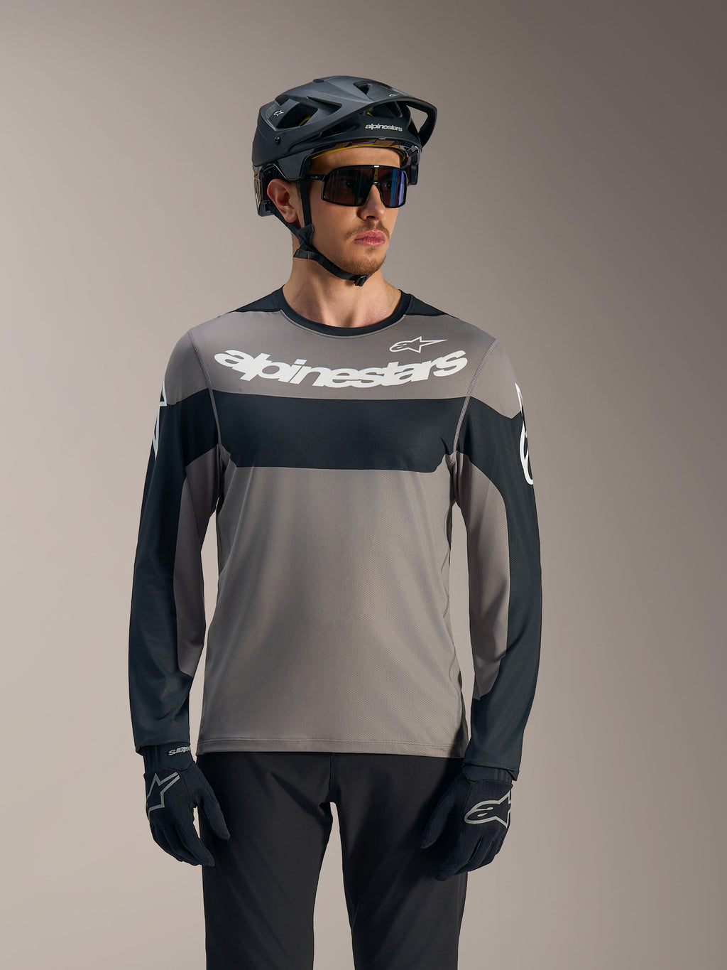 A-Dura Race långärmad tröja i grått och svart med vit Alpinestars-logotyp, matchad med MTB-hjälm för stigcykling.
