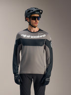 A-Dura Race långärmad tröja i grått och svart med vit Alpinestars-logotyp, matchad med MTB-hjälm för stigcykling.