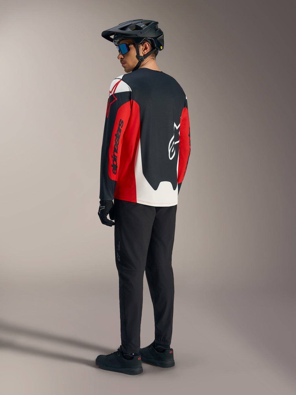 Röd Alpinestars A-Dura Race långärmad tröja med grafik, sedd bakifrån som del av en mountainbike-utrustning.